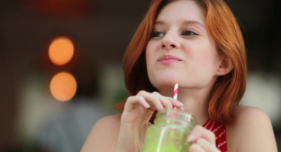 Smiling woman with a green smoothie drink