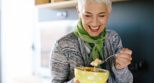 Woman smiling and enjoying a bowl of cereals Woman smiling and enjoying a bowl of cereals