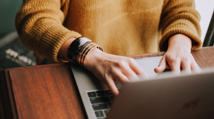 Hands typing on a laptop